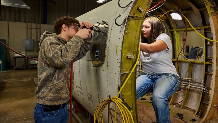 Two students installing window onto plane