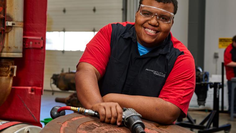 Student working on semi truck trailer hitch 