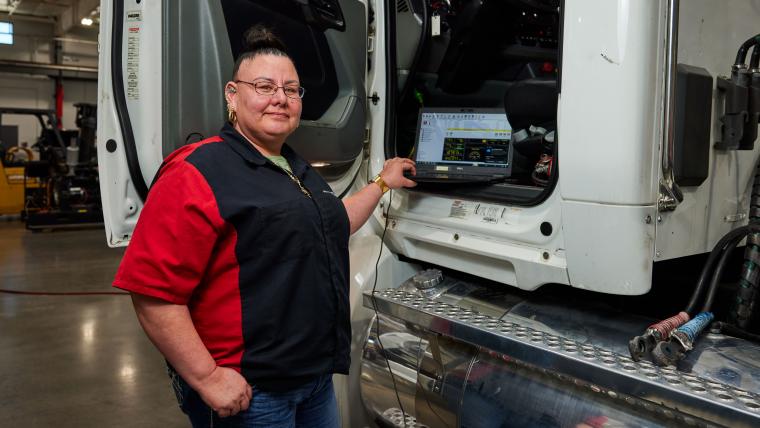 Student using a laptop to read diagnostic information from a semi truck