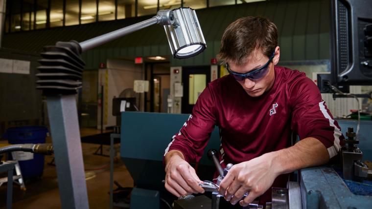 Student measuring a part with calipers
