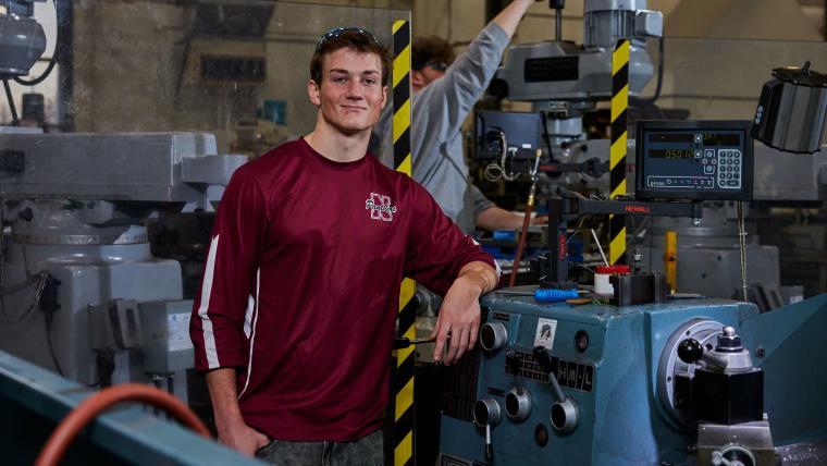 Student standing in front of a lathe