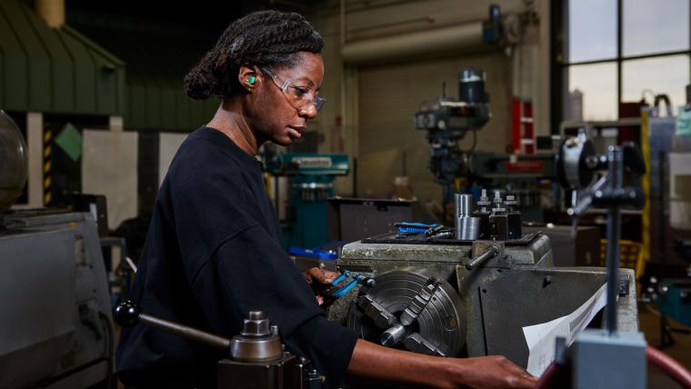 Student reading a document attached to the top of a lathe