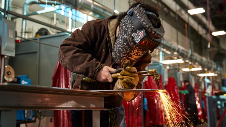 Student cutting piece of steel with a torch
