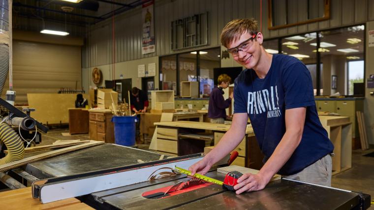 Student setting table saw for cutting wood board
