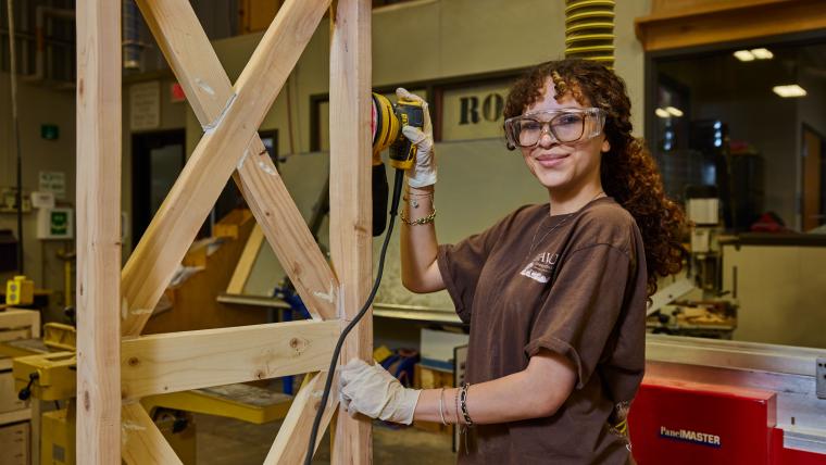 Student sanding wooden post