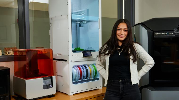 Student standing in front of several 3D printers