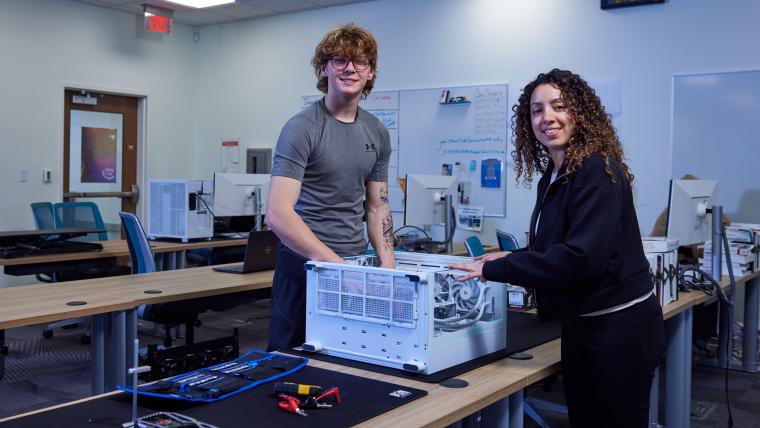 Two students working on the internals of a desktop computer