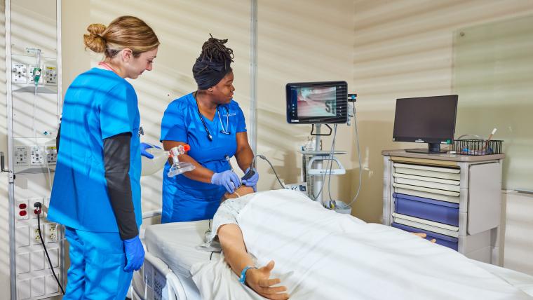 Two students practicing using an endoscopic camera on a training mannequin