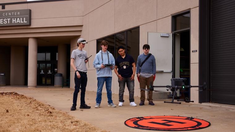 Four students practicing flying a drone
