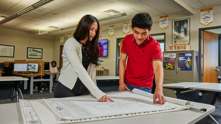 Two students reviewing building blueprints