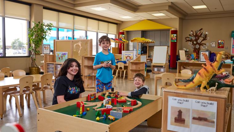 Student and two kids playing with a toy train set