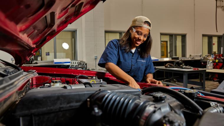 Student working on car from under the hood