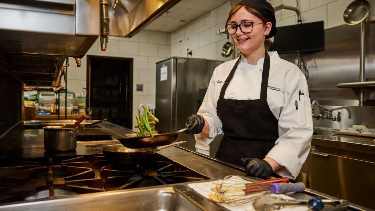 Student cooking asparagus over a stove
