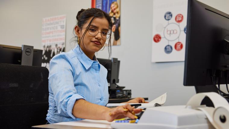 Student keying numbers into a desktop calculator