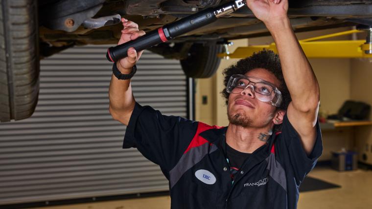 Student working on the underside of a car