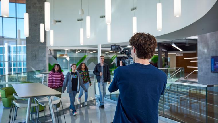 Student recording a group of students using a large video camera