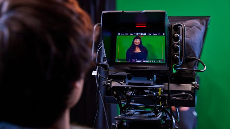 Cinematic camera recording student in front of a green screen