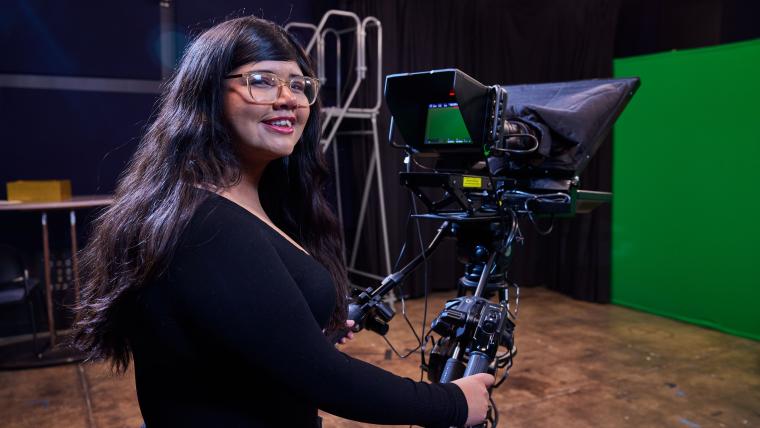 Student operating a cinematic camera on a tripod