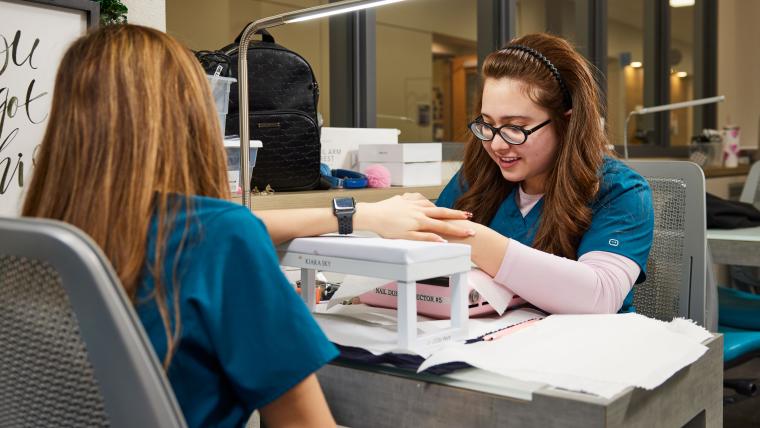 Student inspecting another student's nail clip ons