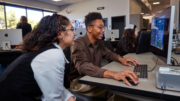 Two students working on a digital flyer
