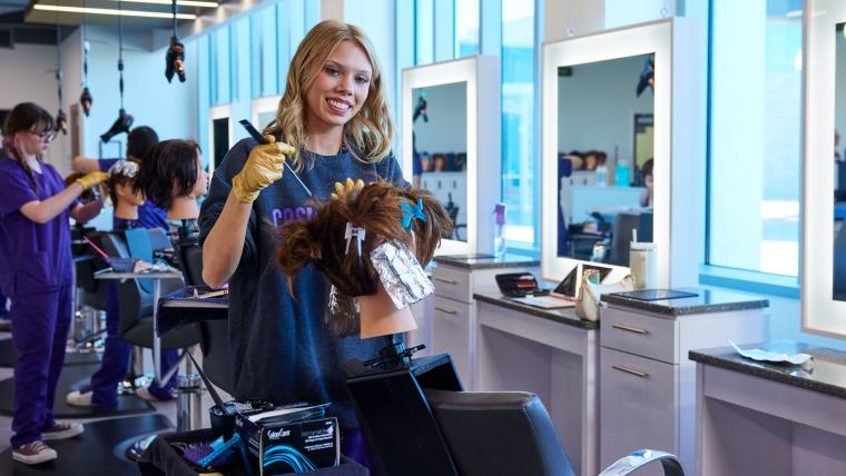 Student combing hair on mannequin head