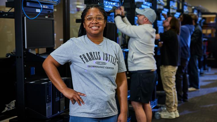 Student standing in front of several server racks