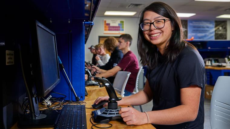 Student operating a computer with a flight joystick