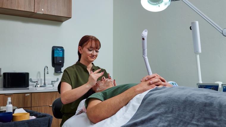 Student applying skincare products to customer's face