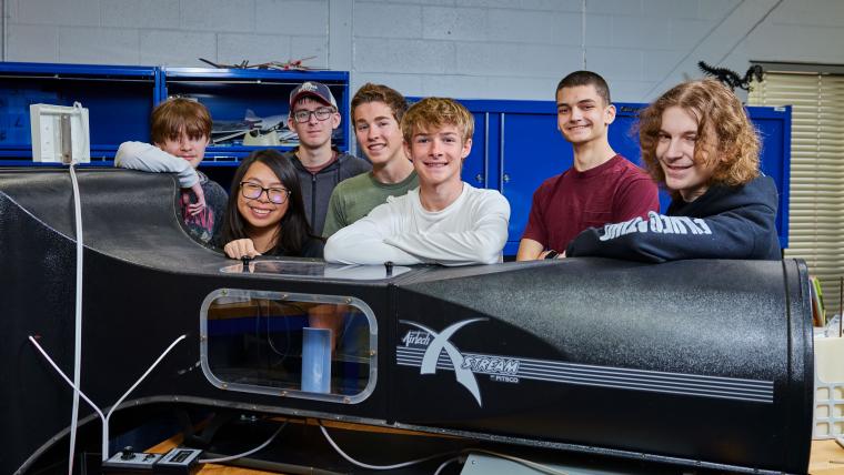 Several students standing behind a wind tunnel