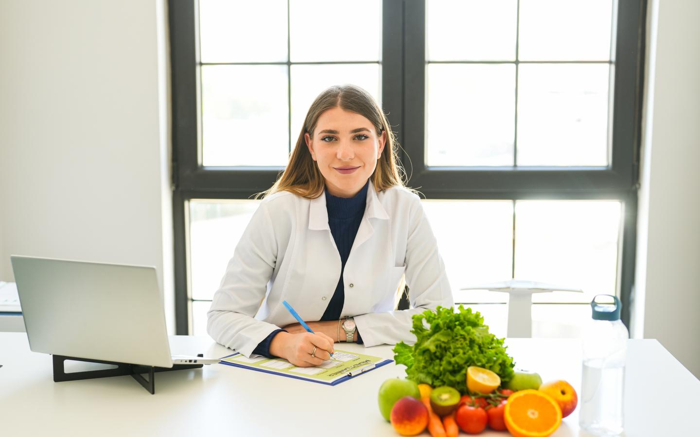 Woman in a labcoat taking notes on a clipboard