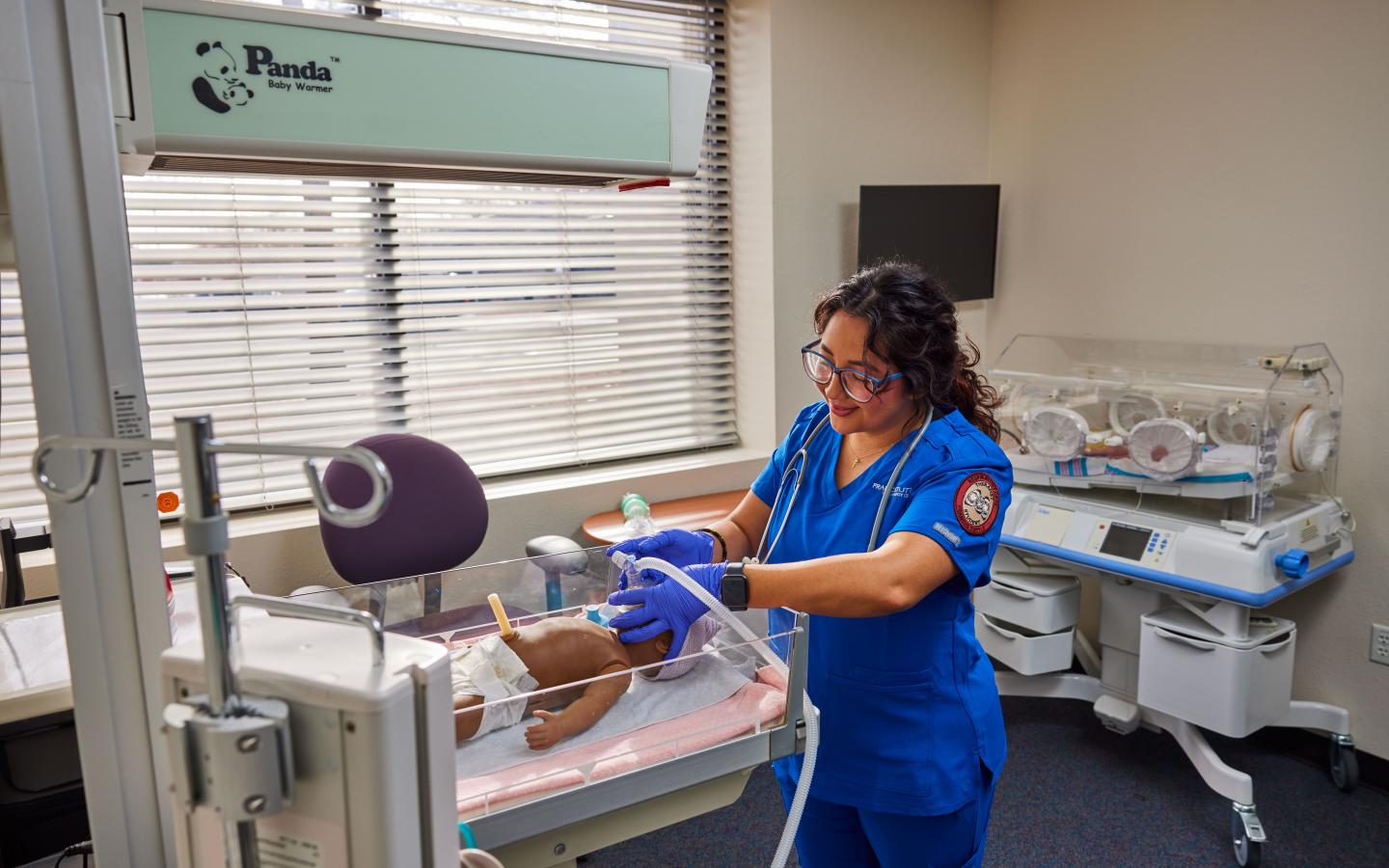 female student using an oxygen machine on an infant mannequin.