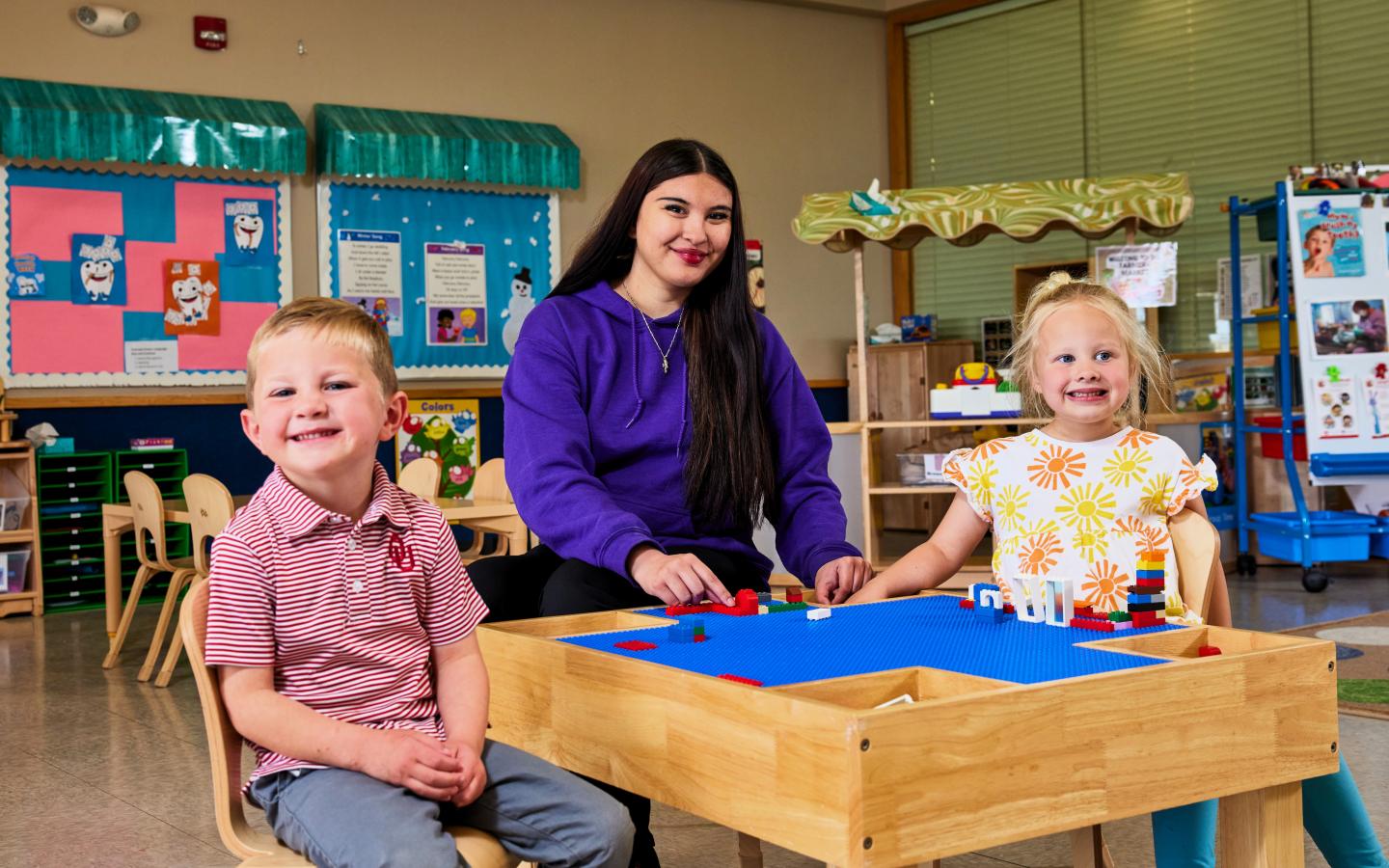 Female student playing legos with two children.