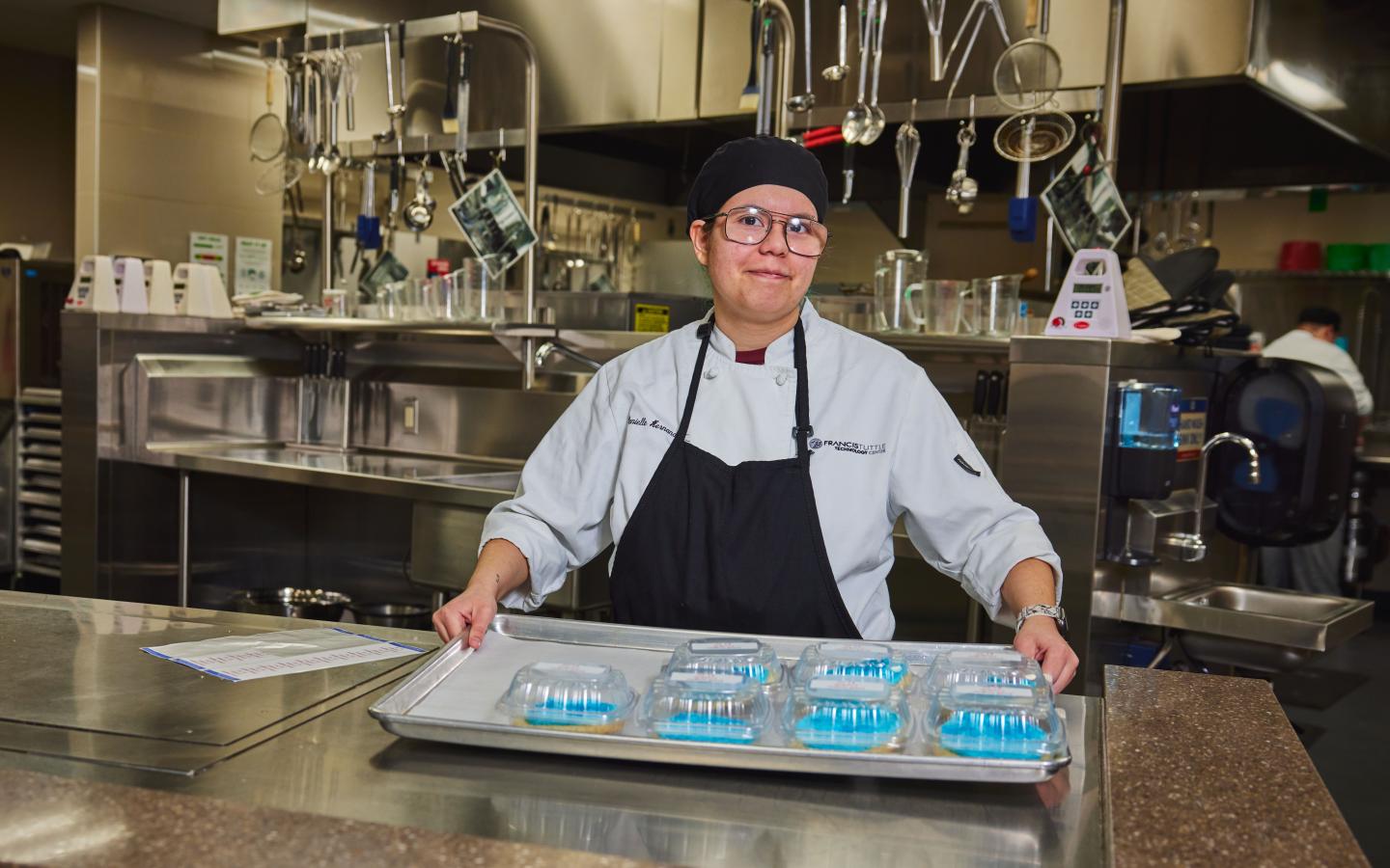 Female student holding a tray of packaged cookies.